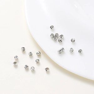 Macro detail of diamond-cut silver spacer beads for DIY jewelry making on white surface
