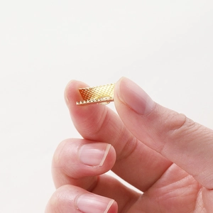 Detail shot of golden ribbon crimps with textured surface and serrated teeth for DIY jewelry