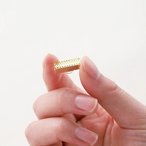 Gold plated ribbon crimp ends with teeth for jewelry making shown on fingertips
