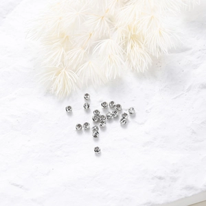 Macro shot of silver faceted spacer beads with spiral texture on white marble base