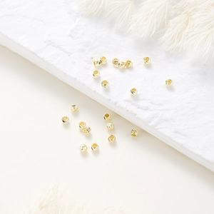 Macro shot of 14K gold-plated textured spacer beads on white stone for DIY jewelry making