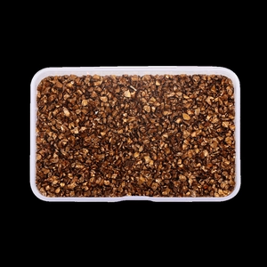 Close-up of irregular bronze glass shards in a clear storage box for DIY nail art
