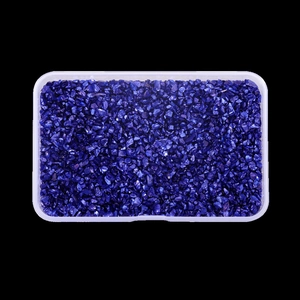 Macro shot of irregular deep purple glass stones in a transparent storage box
