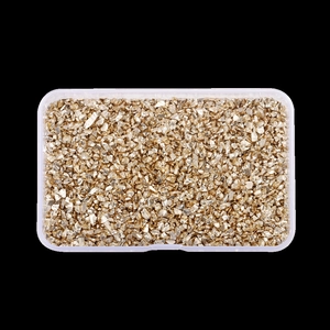 Macro shot of irregular metallic gold glass stones in a clear rectangular container