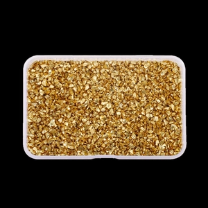 Detailed top view of irregular shiny gold crushed glass stones in a clear plastic storage box
