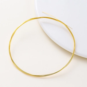 Roll of 14K gold plated copper wire for DIY jewelry making displayed on a white plate