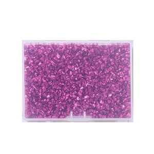 Macro shot of irregular metallic purple glass stones for DIY crafts in a clear box