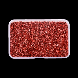 Macro shot of metallic red glass crushed stone in a transparent organizer box