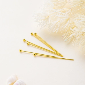 Close-up of 18K gold-plated ball head pins on a minimalist neutral background for jewelry DIY