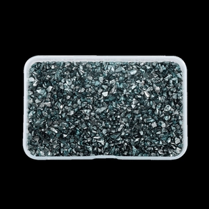 Detail view of irregular dark grey metallic glass crushed stones in a transparent storage box
