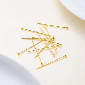 Macro shot of gold ball head pins for jewelry making in a soft white background