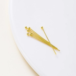 Macro shot of 14K gold plated ball head pins for DIY jewelry making on white tray