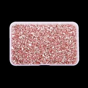Detailed macro shot of rose gold crushed glass stones in a clear plastic storage box