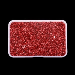 Detailed view of red metallic irregular glass stones in a plastic storage box for nail art