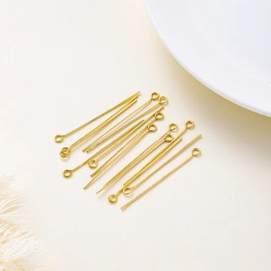 Close-up of 18K gold plated eye pins for DIY jewelry making on white textured fabric