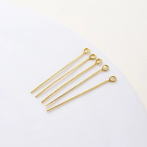 Close-up of five 18K gold-plated eye pins for handmade jewelry making and DIY beadwork