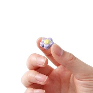 Macro detail of a small acrylic flower bead with pearlescent purple petals and yellow center