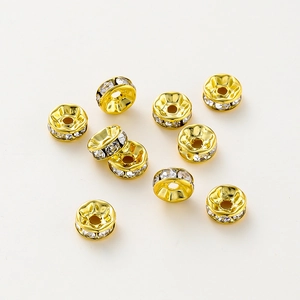 Primer plano de cuentas espaciadoras chapadas en oro con brillantes diamantes blancos