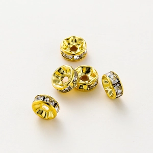 Vista macro de cinco cuentas espaciadoras de strass bañadas en oro de 14K para joyería