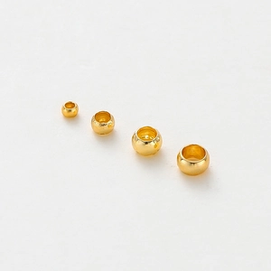 Macro view showing four sizes of 14K gold plated stopper beads for jewelry making