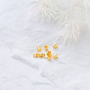 Vue macro de perles d'espacement dorées 14K sur pierre blanche avec fleurs séchées