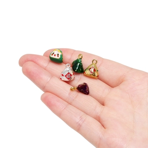 Hand holding five colorful alloy zongzi charms with Fu character for DIY jewelry