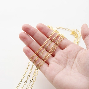 Close-up of 18K gold plated oval paperclip chain on palm showing scale and polished texture