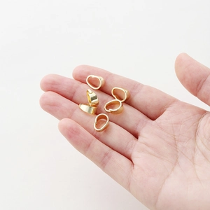 Close-up of five 14K gold-plated bails for necklace jewelry making on a person's hand