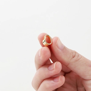 Macro view of 14K gold plated necklace bail connector shown against fingers for size scale