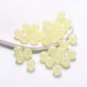 Detailed view of pale yellow acrylic pumpkin beads with vertical stripes for jewelry DIY