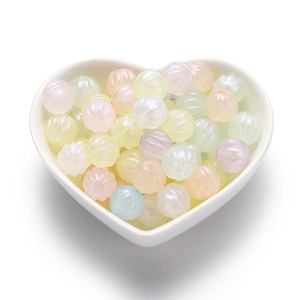 Macro shot of colorful acrylic pumpkin beads for DIY jewelry in a heart shaped dish