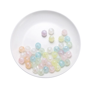 Close-up of pastel macaron acrylic pumpkin beads with pearlescent finish in a white dish
