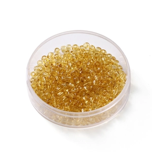 Gros plan de perles de rocaille ambrées de 4 mm dans une boîte ronde pour bijoux DIY