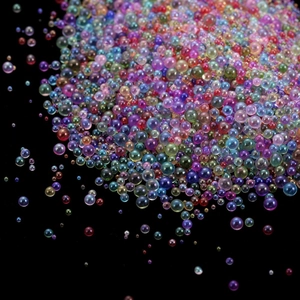 Macro shot of iridescent mixed-size glass bubbles for DIY crafts and nail art decor