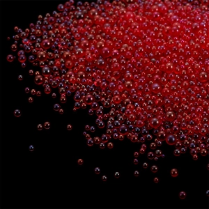 Macro shot of vibrant red translucent iridescent glass bubble beads on black background