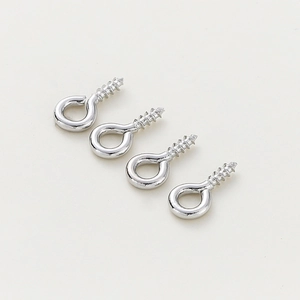 Close-up of four silver screw eye pins for jewelry making on a grey background