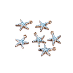 Detailopname van zes blauwe en gouden zeester bedeltjes met emaille textuur voor DIY sieraden
