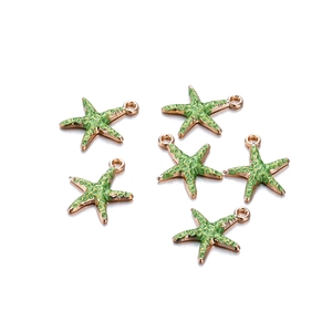 Detail van zes roségouden zeesterhangers met groen email en ronde ophangringen