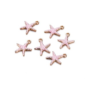 Macro-opname van 6 roze emaille zeesterbedeltjes met gouden legering voor DIY-sieraden