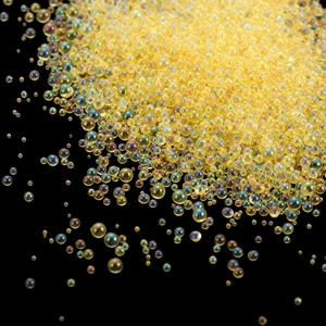 Macro shot of mixed size yellow iridescent glass bubble beads for DIY resin craft