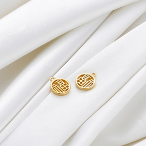 Close-up of 18K gold plated Fu character pendants on elegant white silk fabric