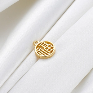Detail of 18K gold plated Fu character pendant on white silk background with hollow design