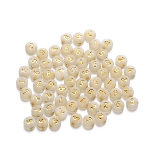 Dettaglio di perline in acrilico bianco opaco con numeri dorati per creazione gioielli