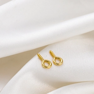 Close-up of 14K gold plated screw eye pins for jewelry making on white silk