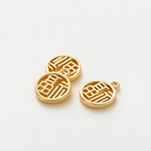 Macro detail of three 18K gold-plated Fu pendants with hollow Chinese lucky characters
