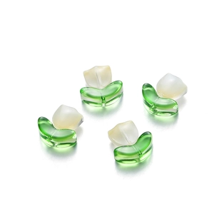 Close-up of four tulip-shaped glass beads for DIY jewelry with white and green petals