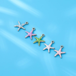 Detailweergave van vijf kleurrijke emaille zeesterbedeltjes met gouden basis voor sieraden