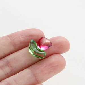 Macro view of a handmade glass tulip bead with pink glitter and green leaves for DIY jewelry