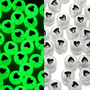 Perline acriliche fluorescenti con cuore nero mostrate in condizioni di luce e buio