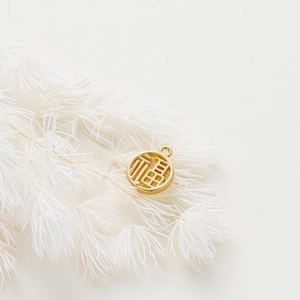 Macro detail of 18K gold plated Fu pendant with intricate hollow design for DIY jewelry